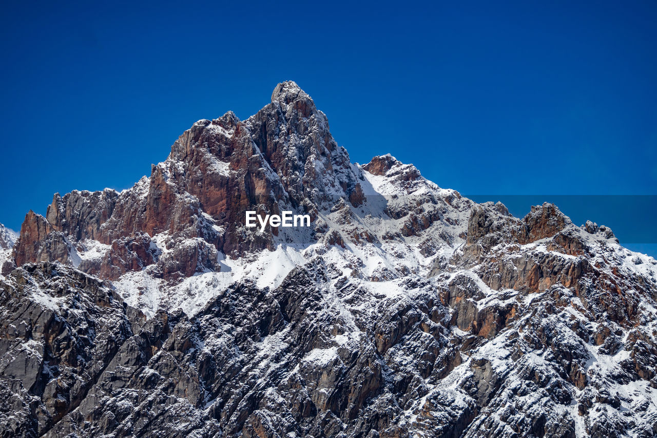 low angle view of snow covered mountain against clear blue sky