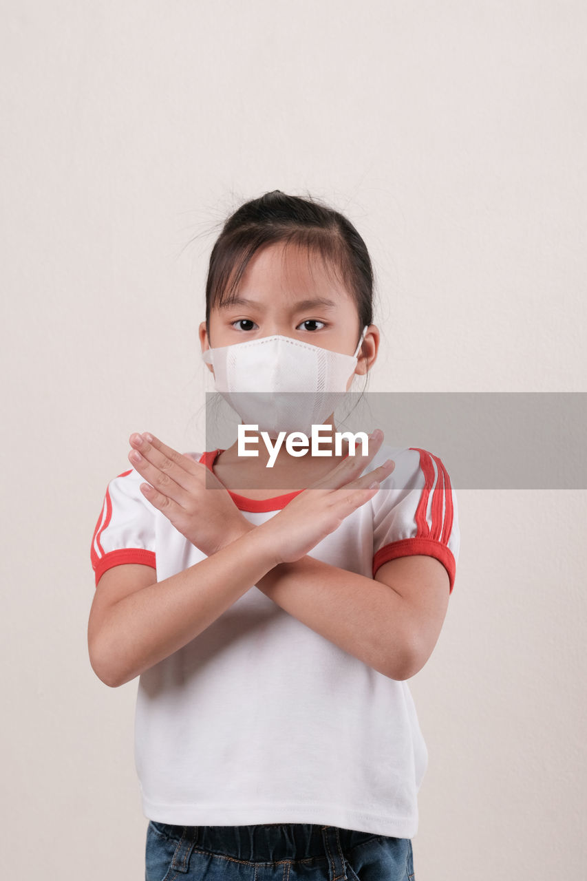 PORTRAIT OF GIRL WEARING MASK AGAINST WHITE BACKGROUND