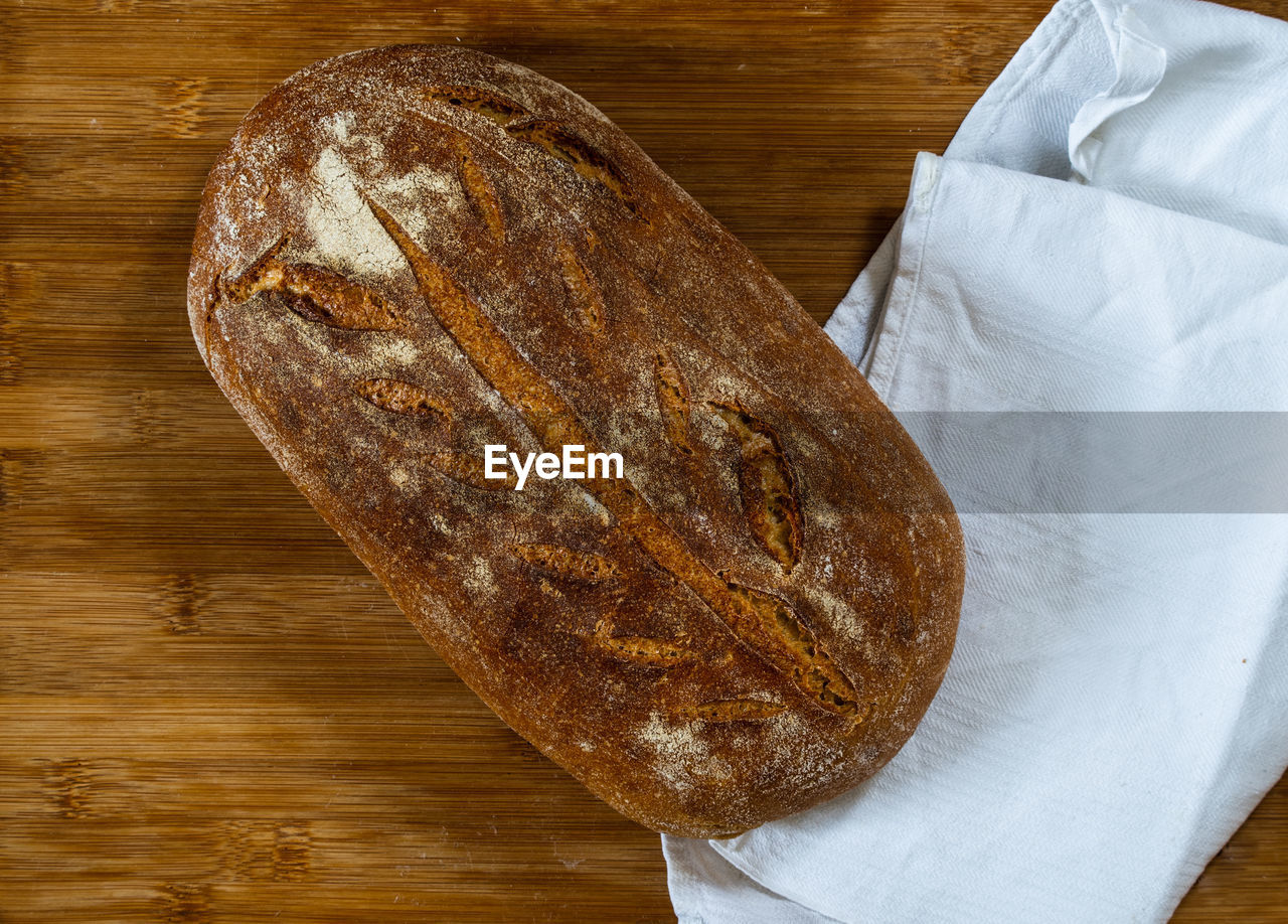 food and drink, wood, food, rye bread, bread, loaf of bread, table, indoors, freshness, no people, high angle view, baked, sourdough, baguette, directly above, close-up, still life, wellbeing, brown, cutting board, healthy eating, ciabatta, whole grain