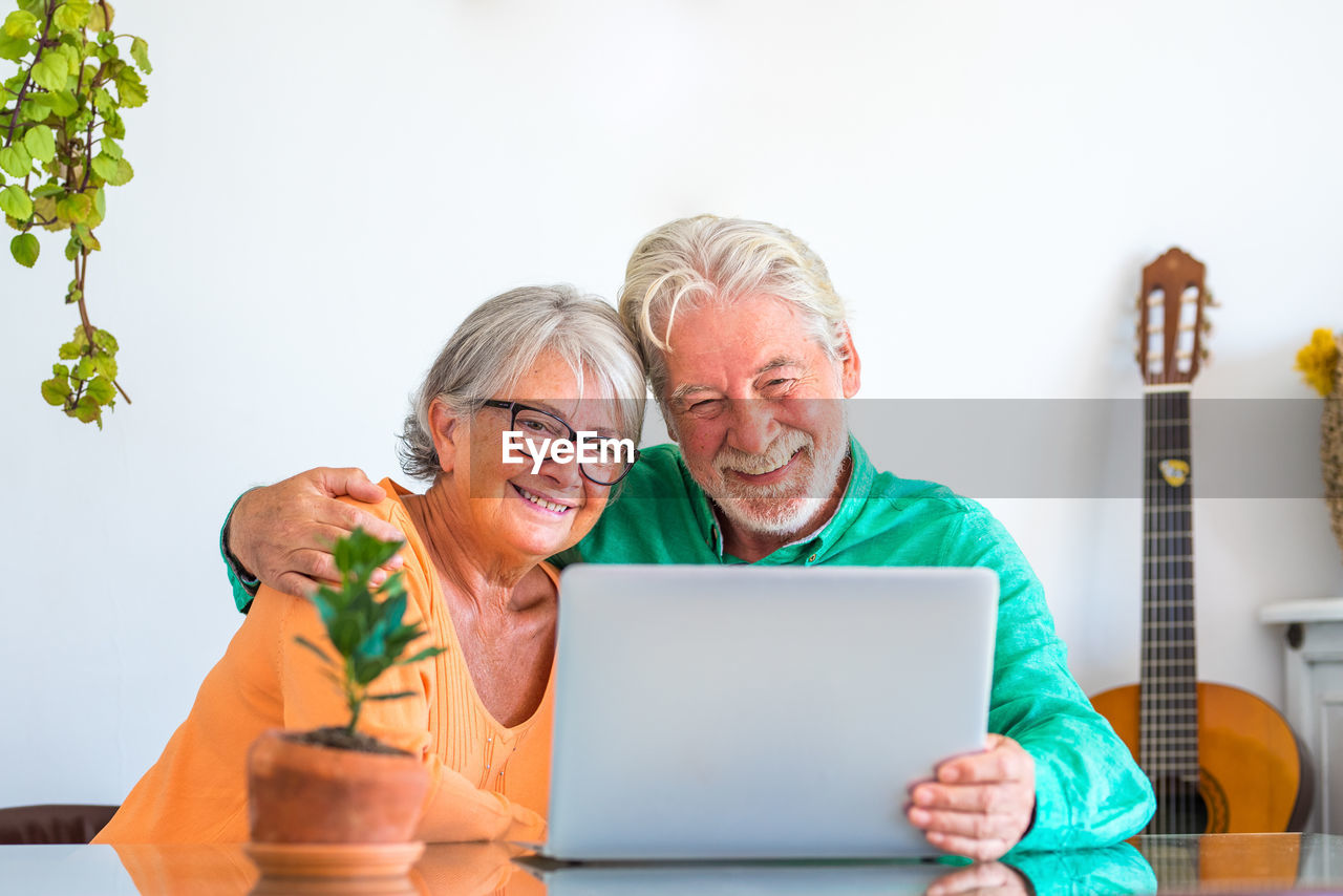 smiling woman using laptop while sitting on table against white background