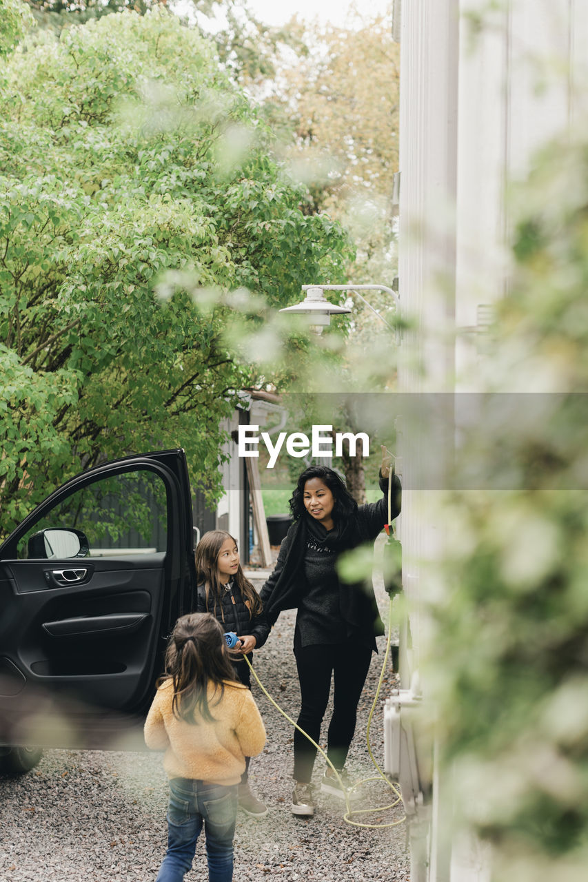 Woman with daughters at electric car charging station