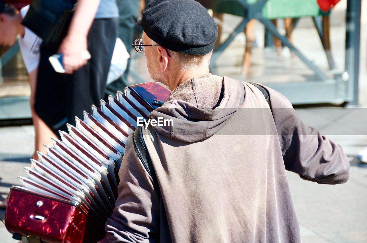 Man playing accordion while standing in city