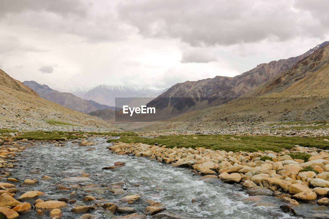 Scenic view of river by mountains against sky