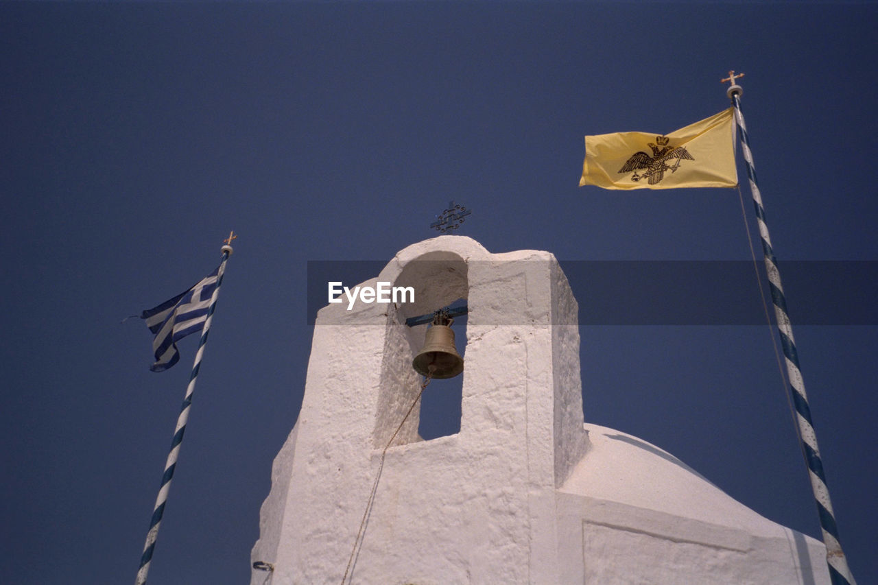 Low angle view of greek flag and bell tower against clear sky