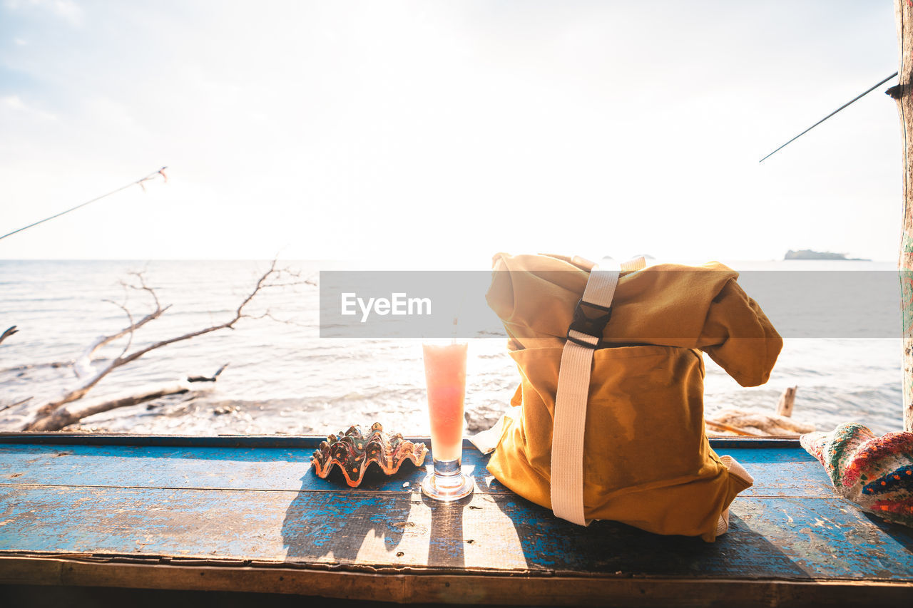 Close-up of of backpack with juice against sea