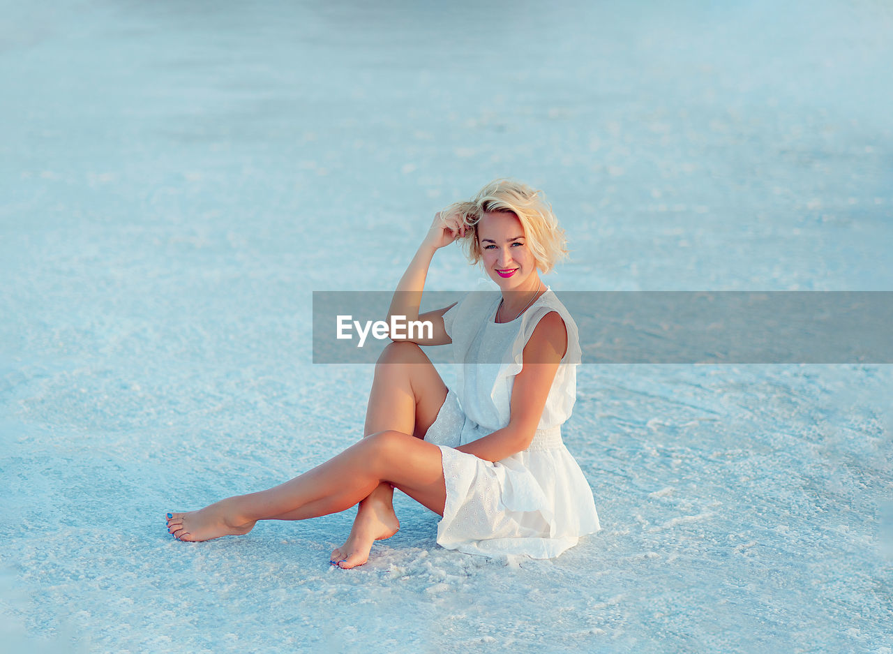 Beautiful girl in a white dress on white sand