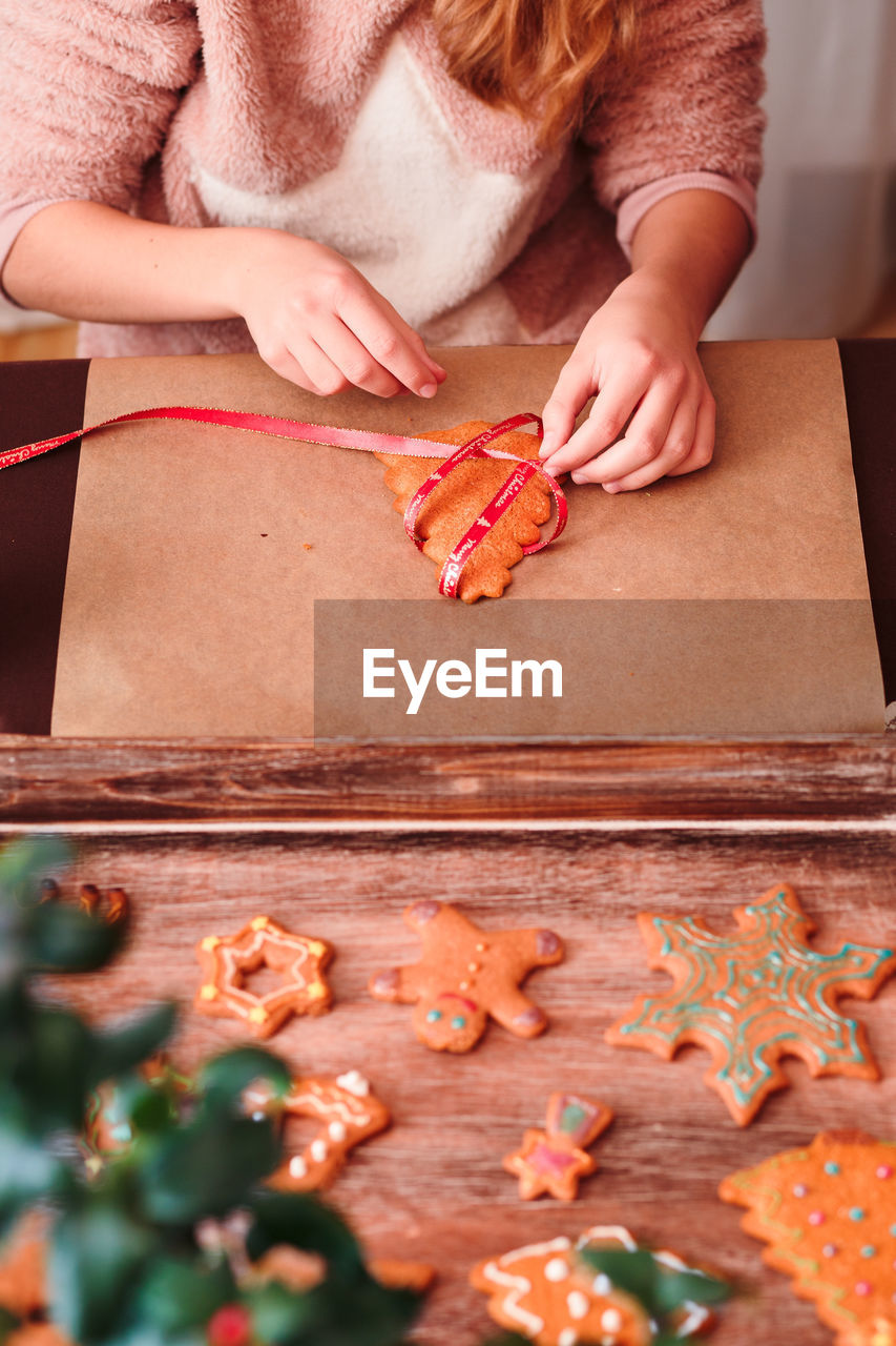 Midsection of woman preparing gingerbread cookies on cutting board