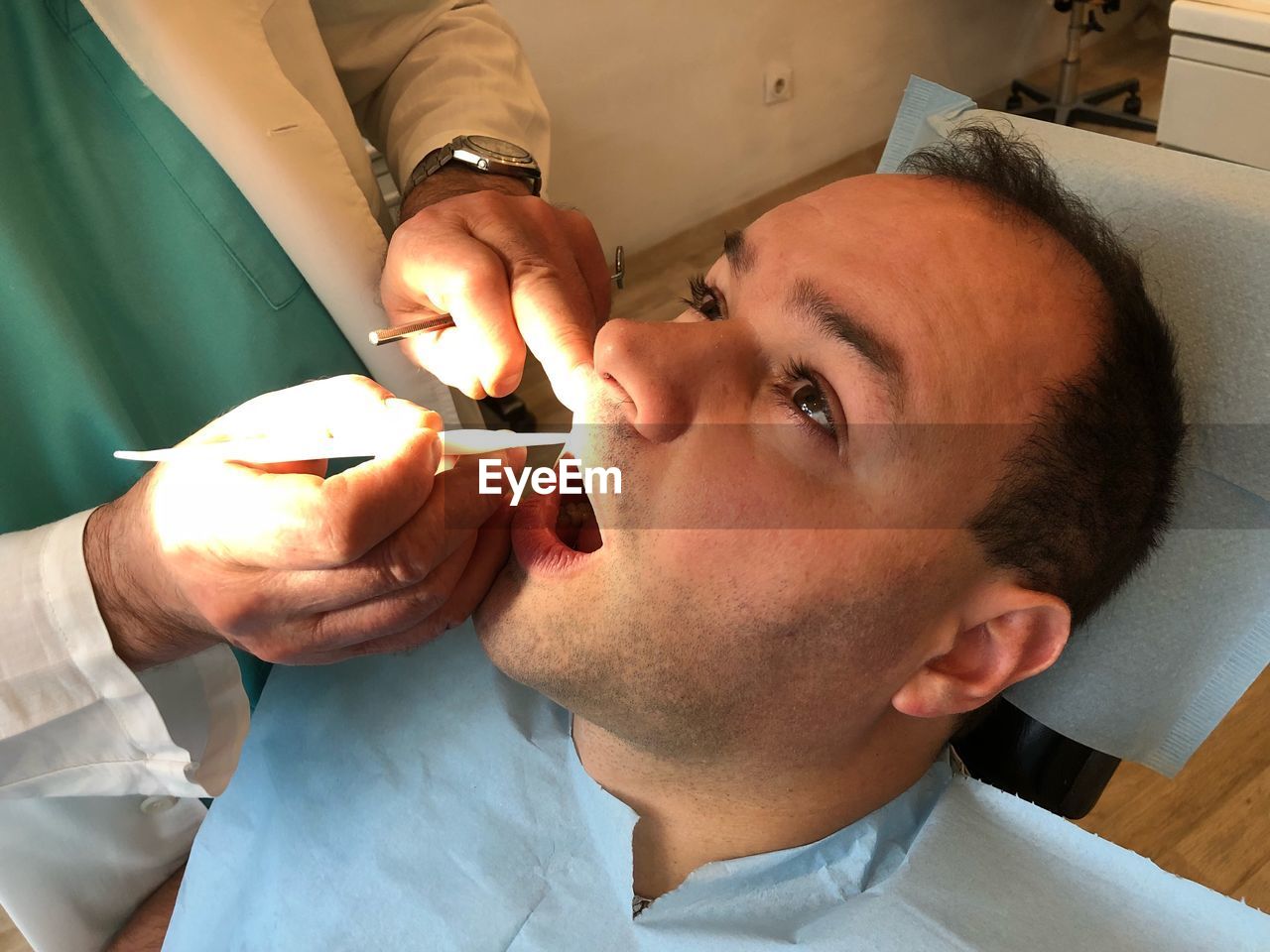 Midsection of male dentist examining patient in clinic
