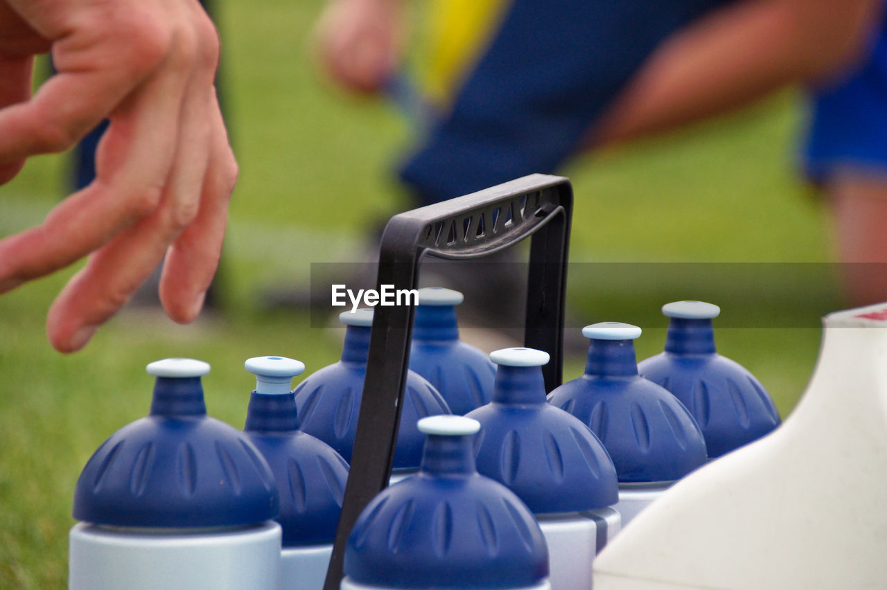 Cropped hand reaching blue bottles outdoors