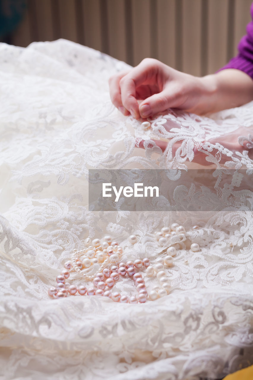 Cropped hands of woman stitching wedding dress