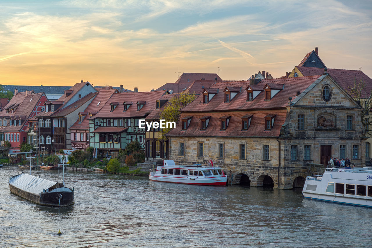 Water taxi in canal by buildings at dusk