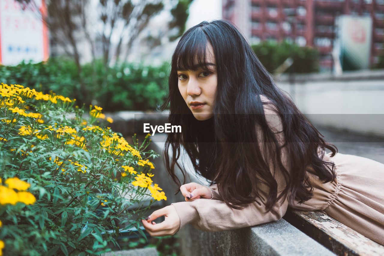 PORTRAIT OF BEAUTIFUL YOUNG WOMAN WITH YELLOW FLOWERS