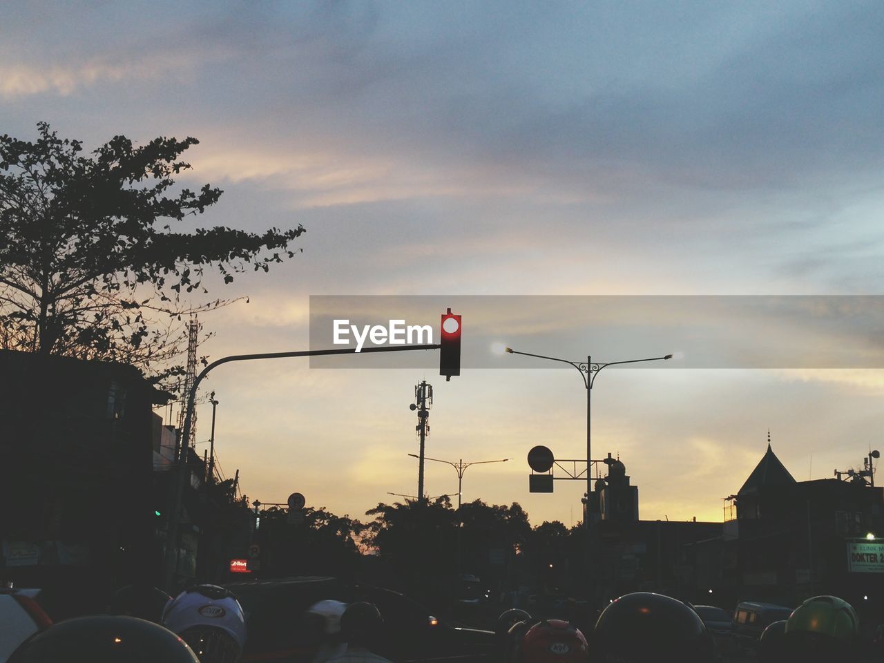 Vehicles on road against cloudy sky during sunset