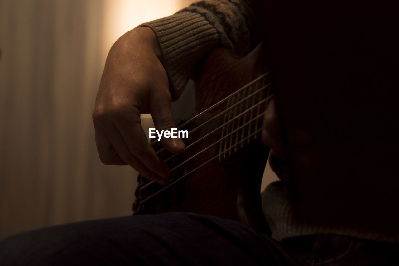 Cropped image of person playing guitar at home