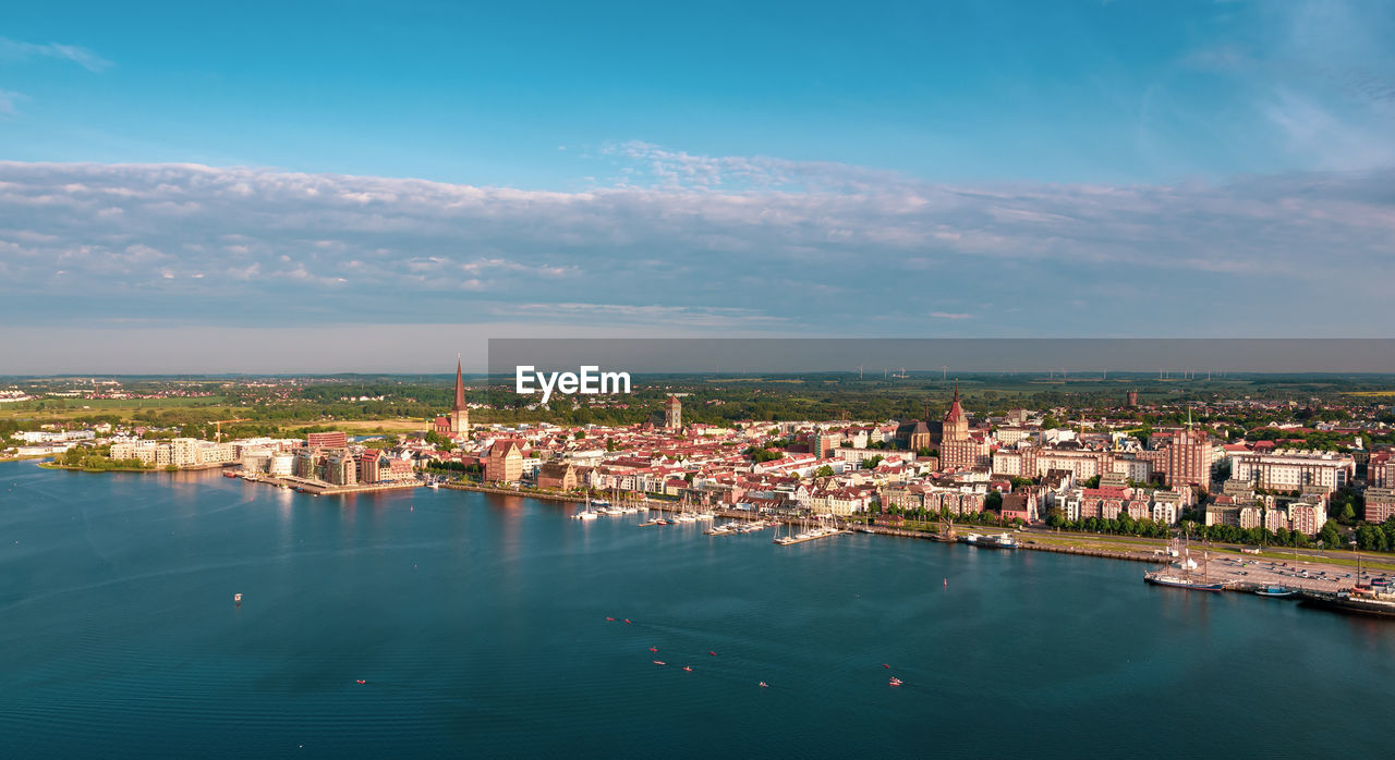 HIGH ANGLE VIEW OF BUILDINGS BY SEA AGAINST SKY