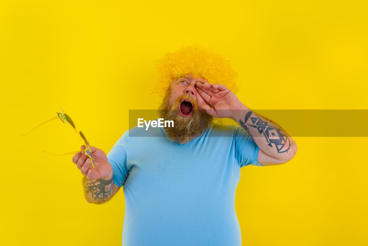 Midsection of man holding yellow against orange background