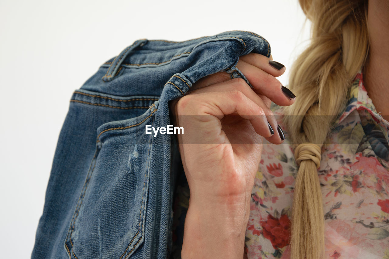 Midsection of woman holding jeans against white background