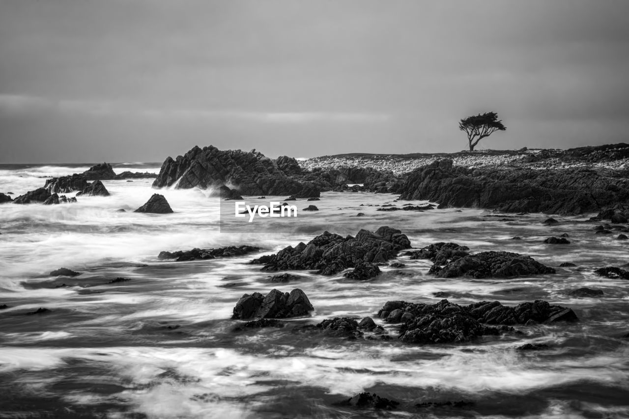 ROCKS ON SHORE AGAINST SKY