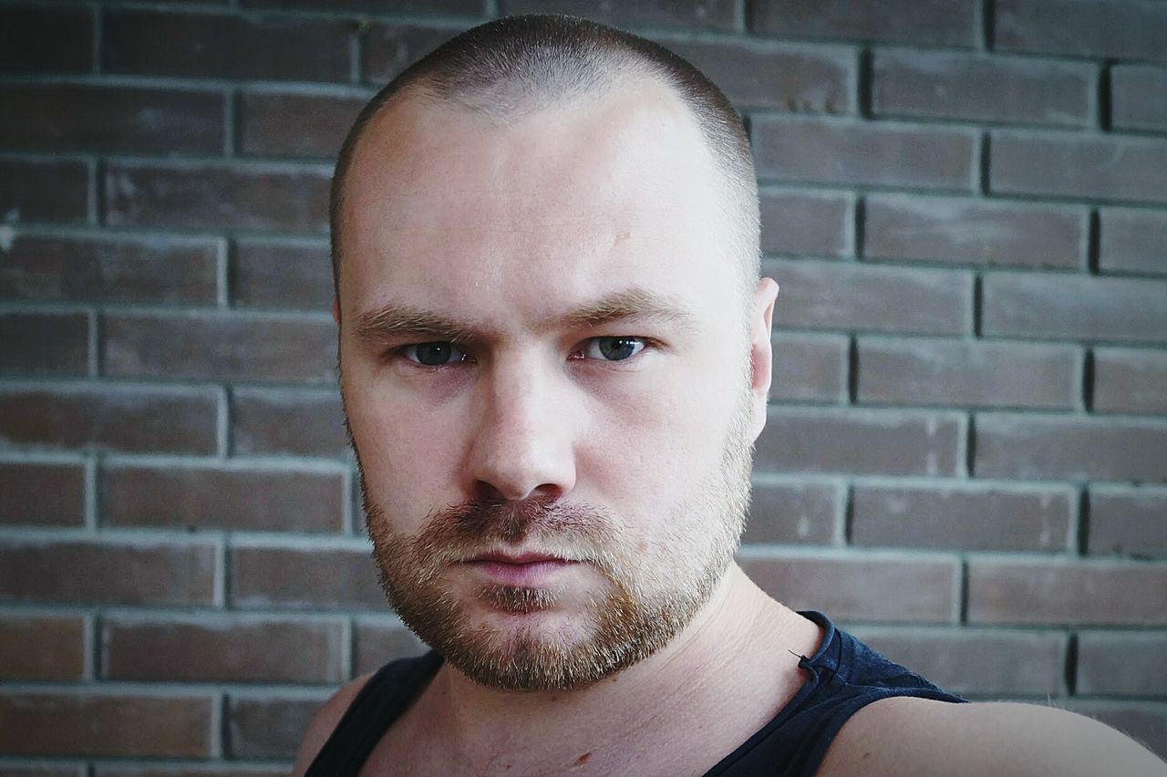 Close-up portrait of man against brick wall