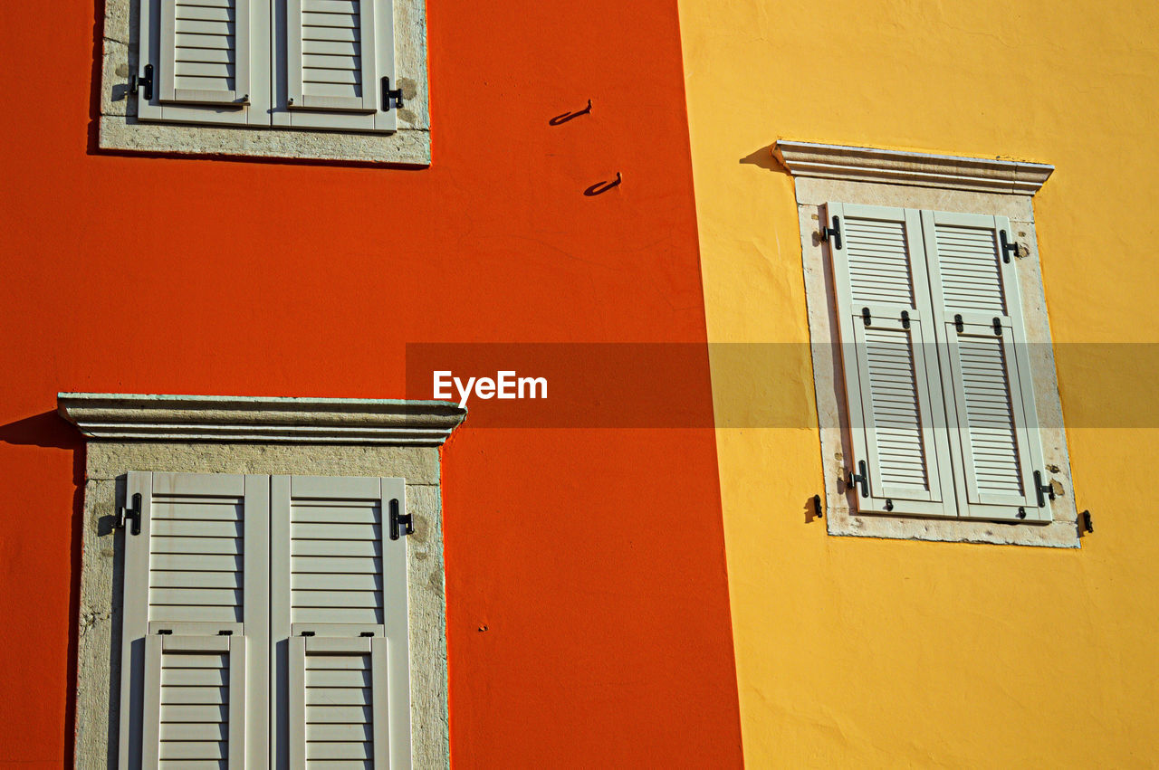 LOW ANGLE VIEW OF CLOSED WINDOW ON ORANGE WALL