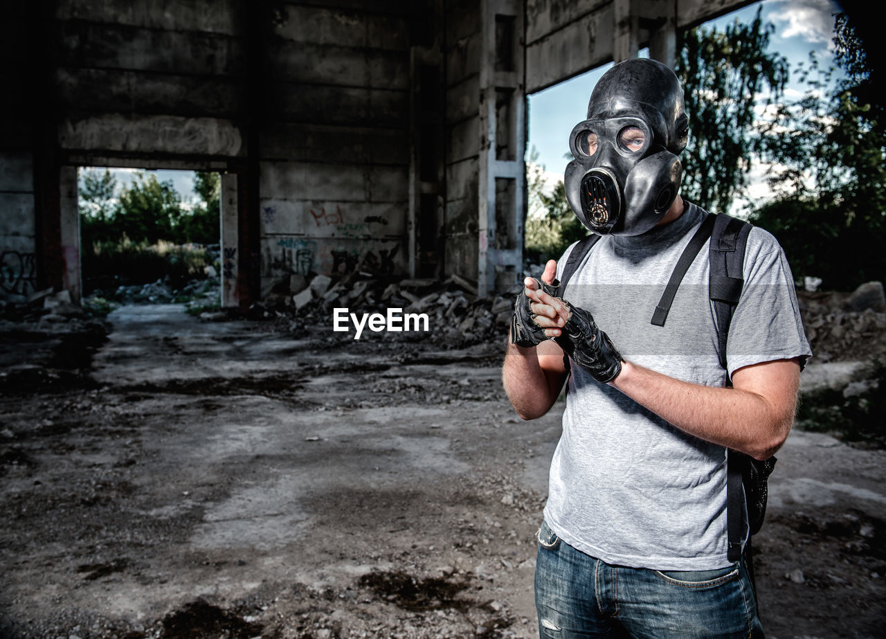 Man wearing gas mask standing under bridge