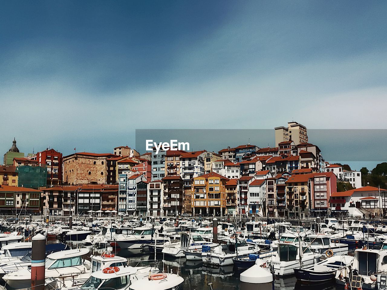 Boats moored in harbor against  old town view