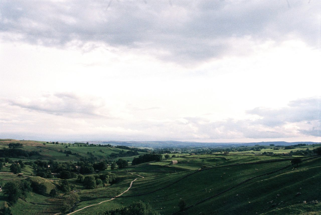 Scenic view of fields against cloudy sky