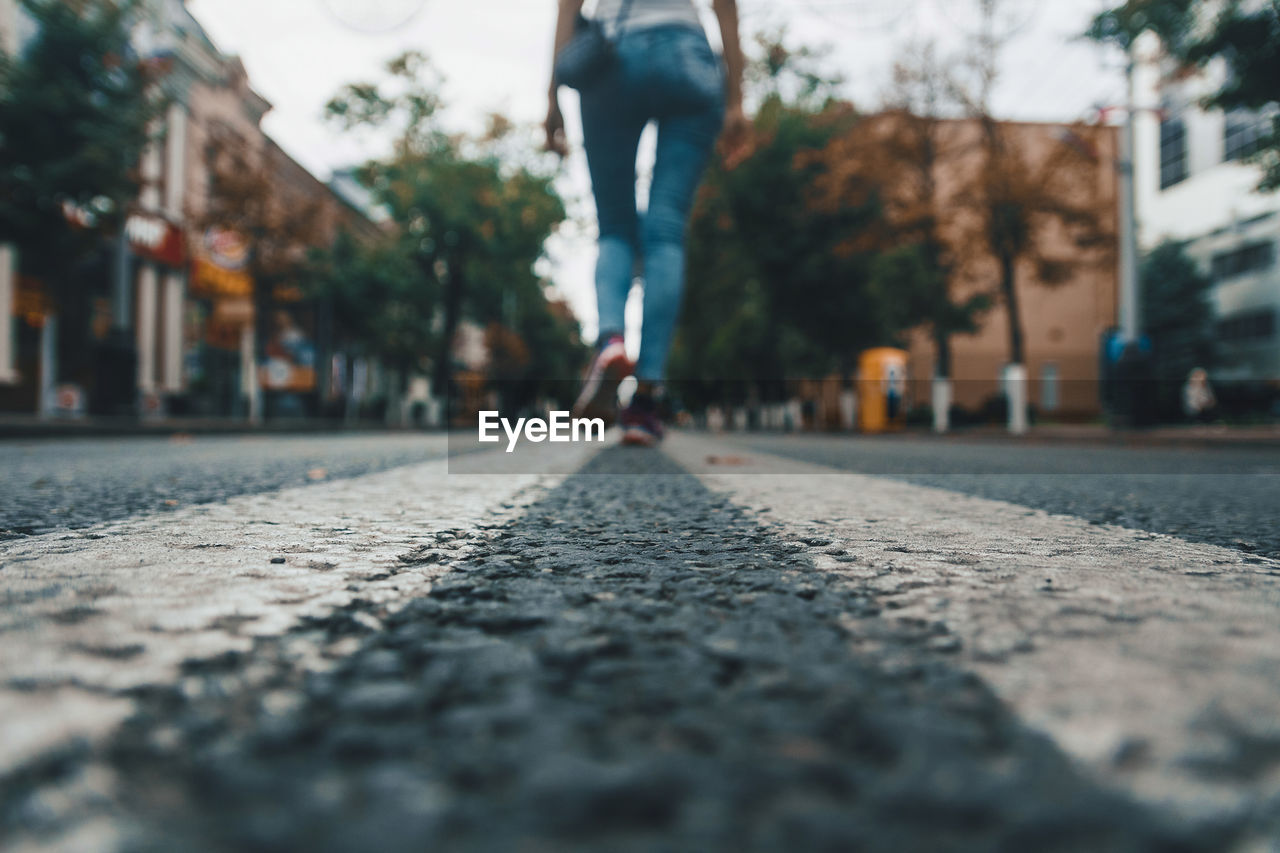 Surface level of woman walking on street in city