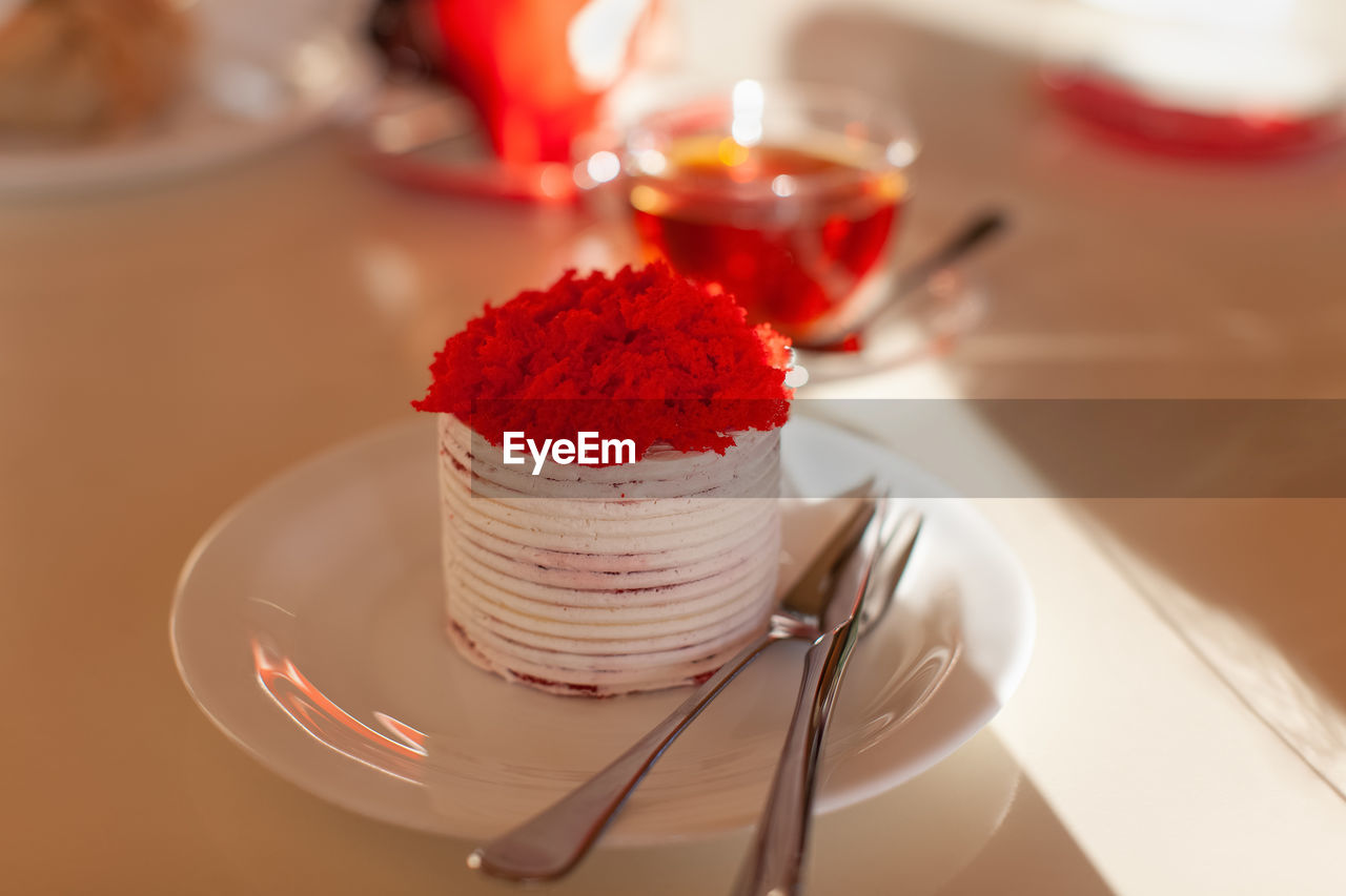 Festive dessert, red velvet cake on table in cafe, in sunlight. single round cake topped