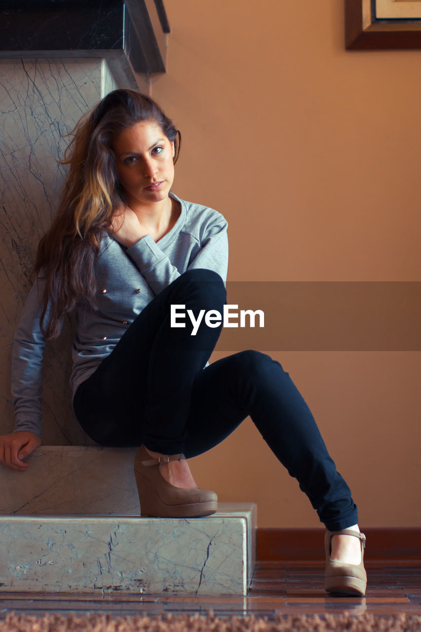 PORTRAIT OF BEAUTIFUL YOUNG WOMAN SITTING ON FLOOR