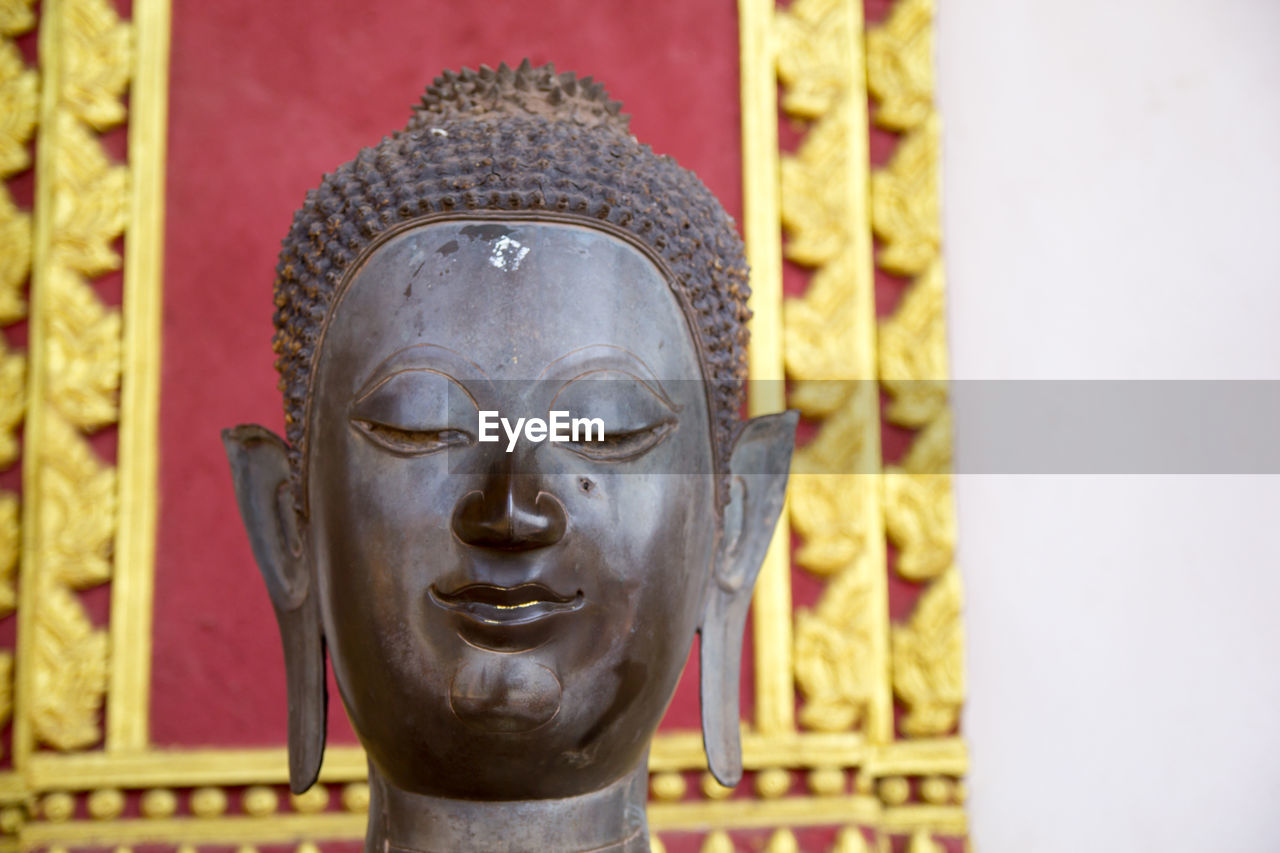 CLOSE-UP OF STATUE OF BUDDHA AGAINST BUILDING