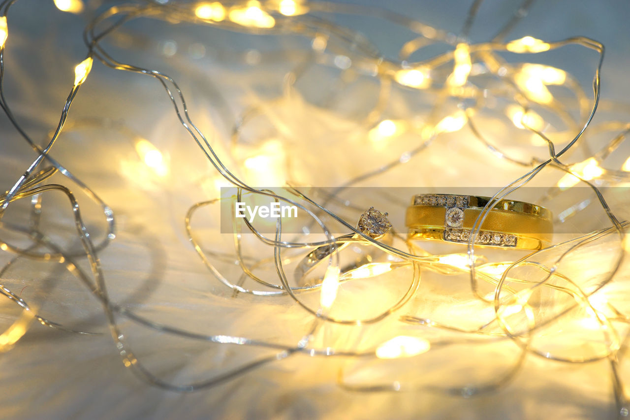 Close-up of engagement rings by illuminated string lights