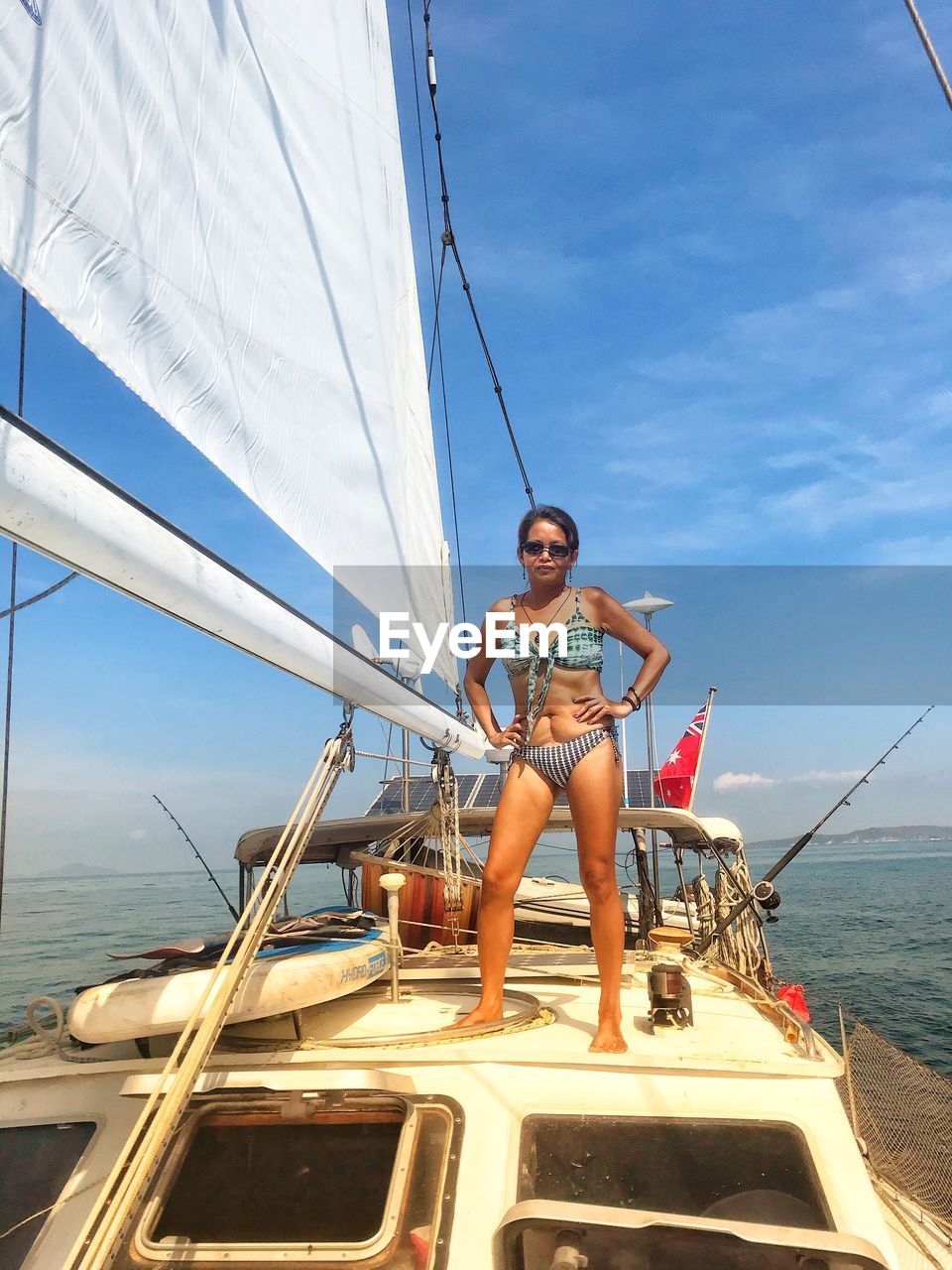 Full length of woman wearing bikini standing on ship against sky