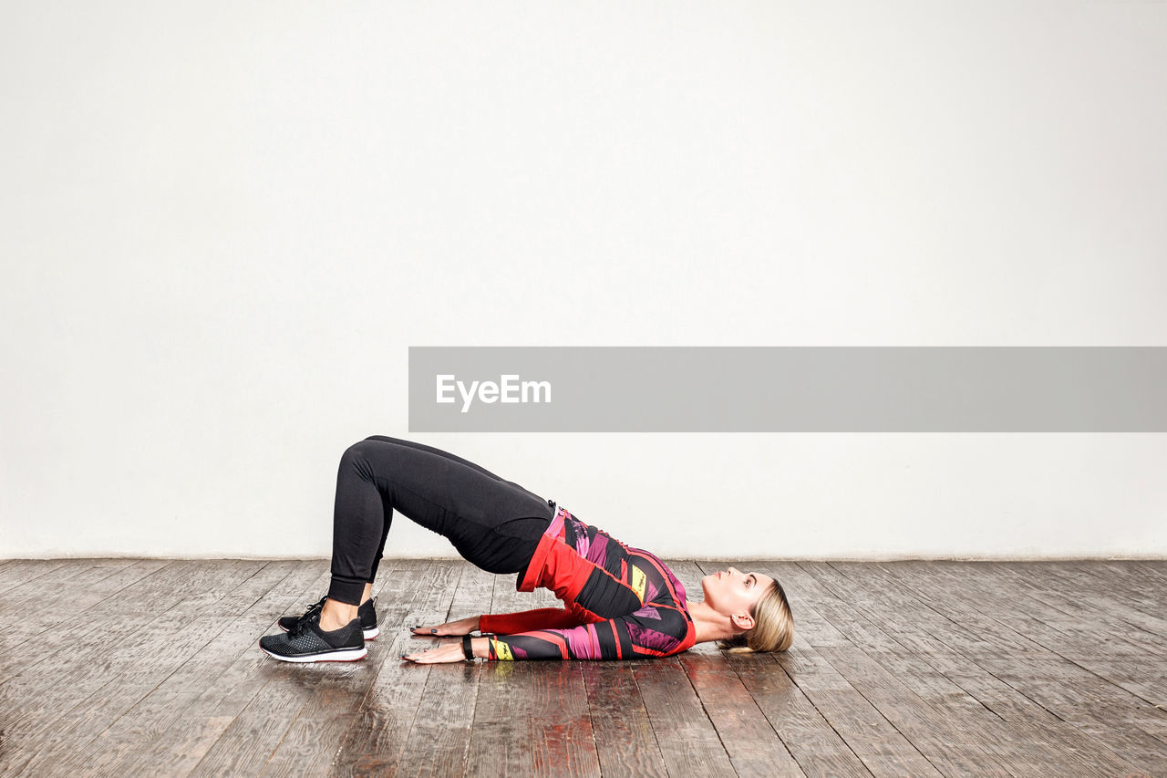 Young woman lying on floor against wall