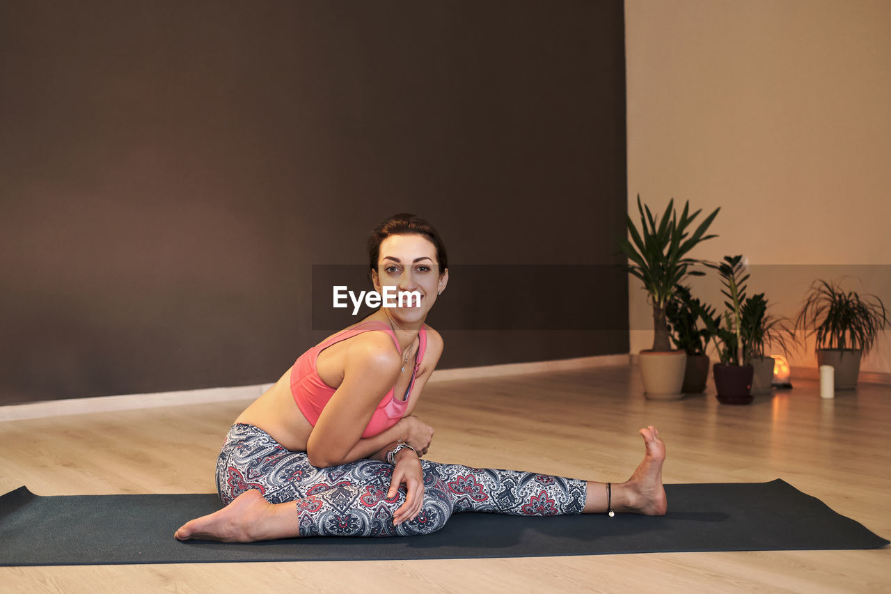 Young woman doing yoga on yoga mat in atmospheric yoga studio