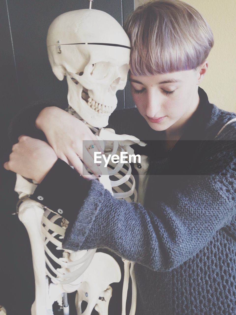 Sad teenage boy hugging skeleton