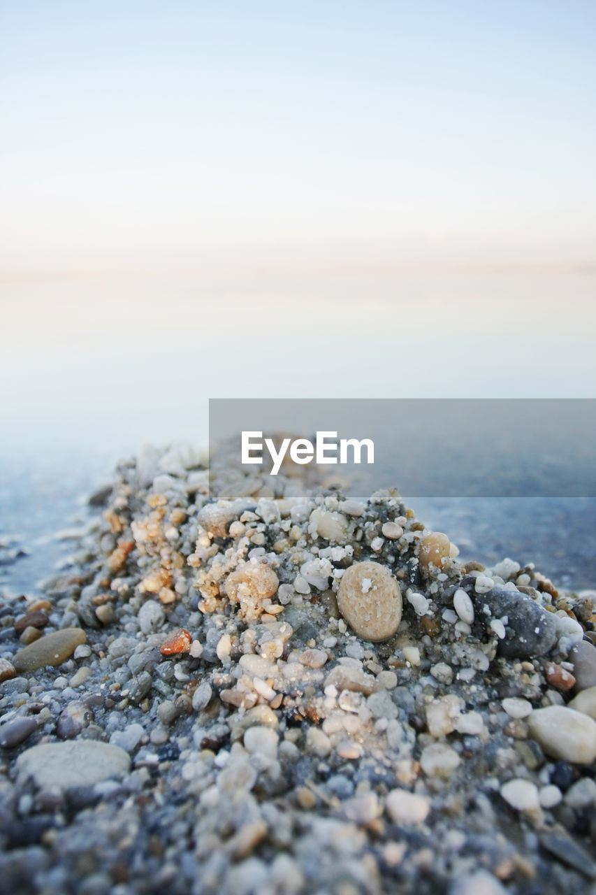 Close-up of stones at beach against clear sky