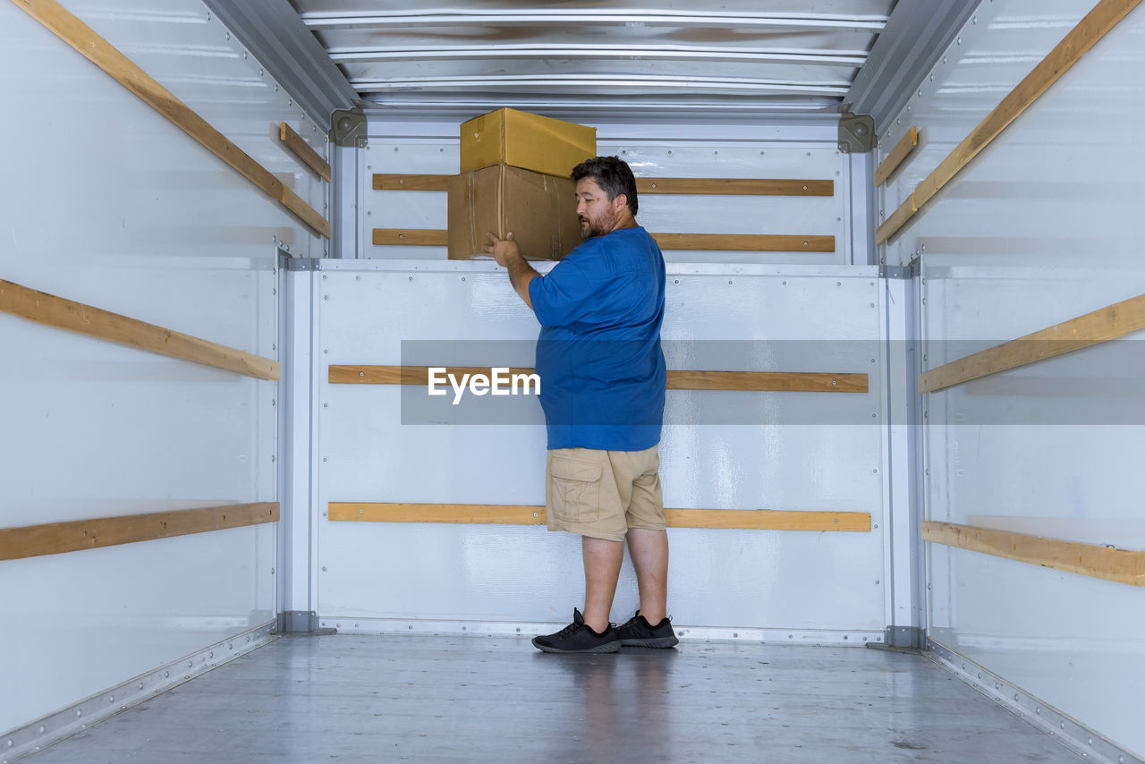 FULL LENGTH REAR VIEW OF MAN STANDING AT HOME BUILDING