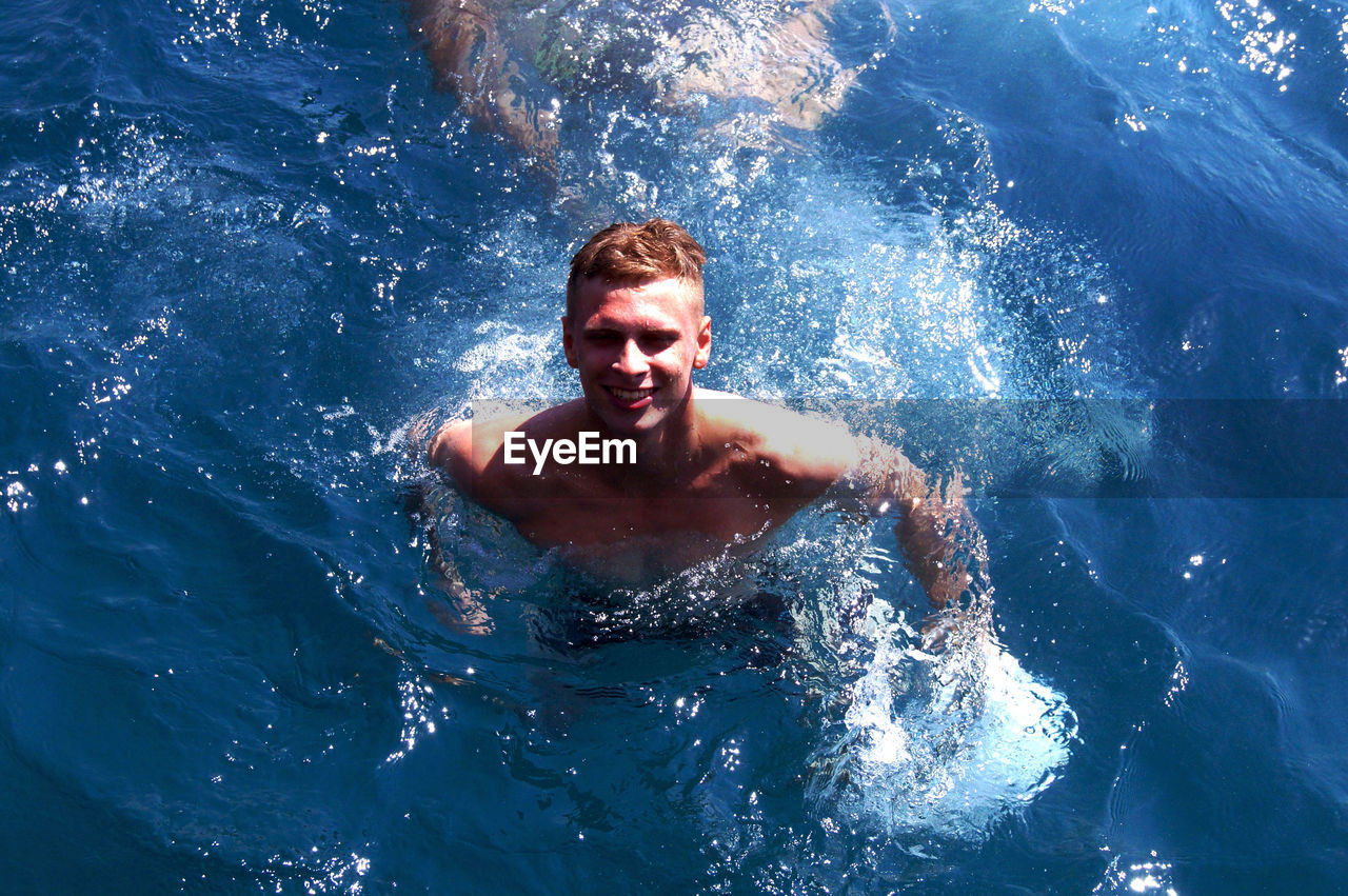 PORTRAIT OF MAN SWIMMING IN POOL