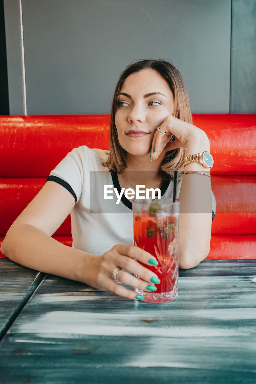 Portrait of smiling young woman drinking glass