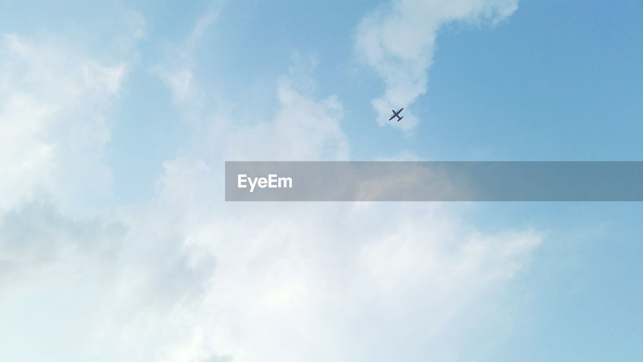 Low angle view of airplane flying against cloudy sky