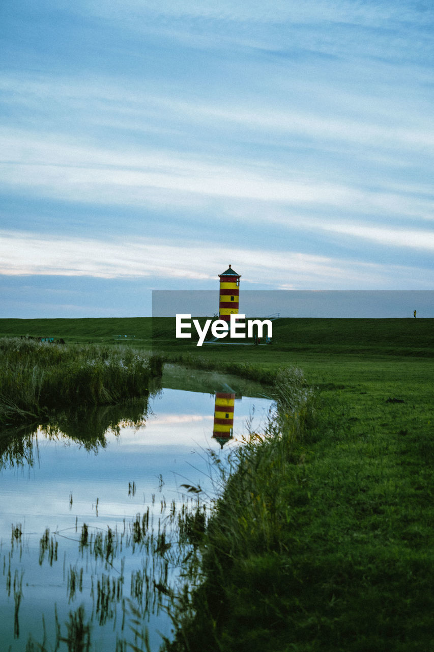 lighthouse by lake against sky