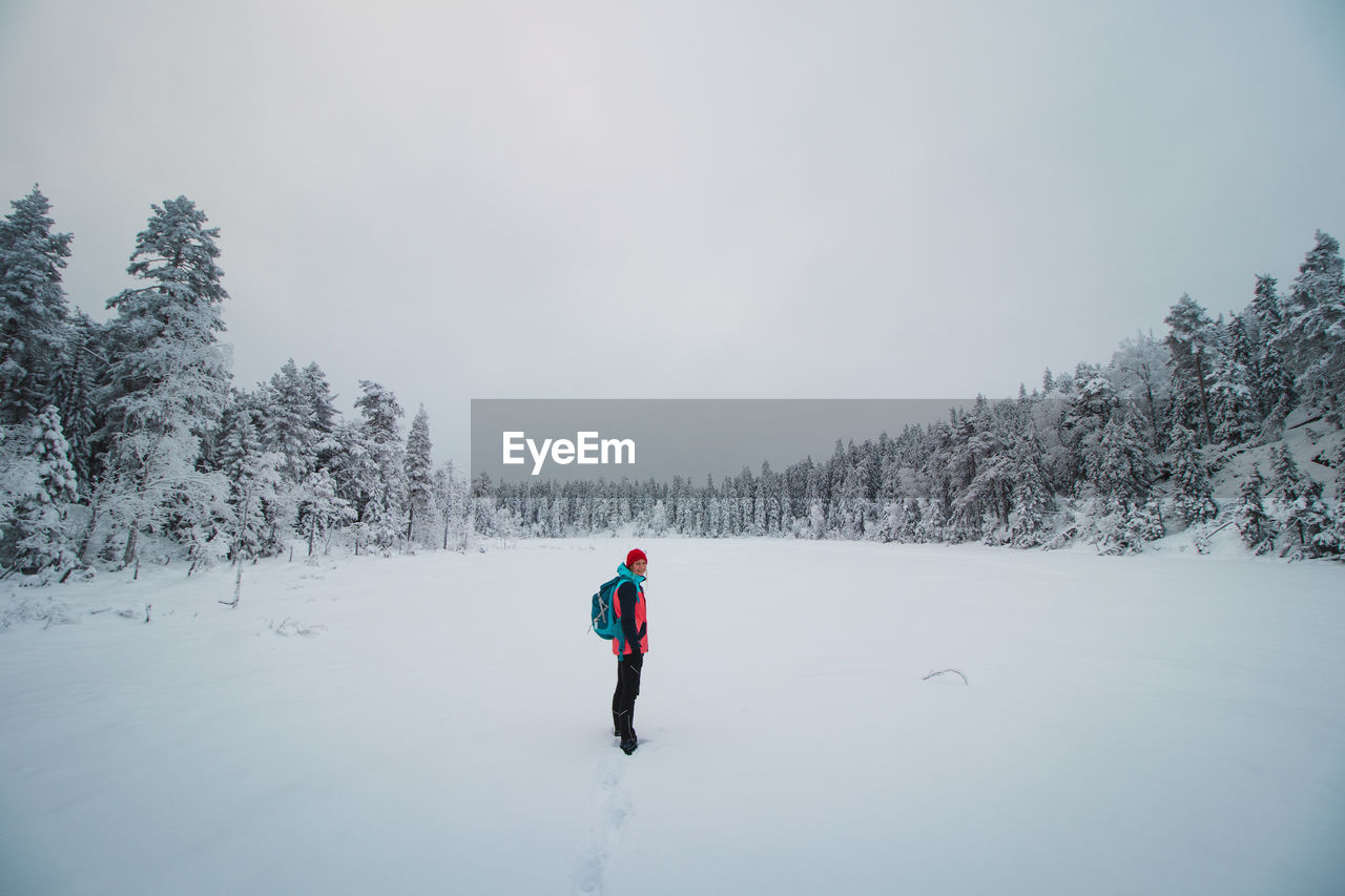 Young explorer in colorful jacket stands in frosty white environment in sotkamo, finland