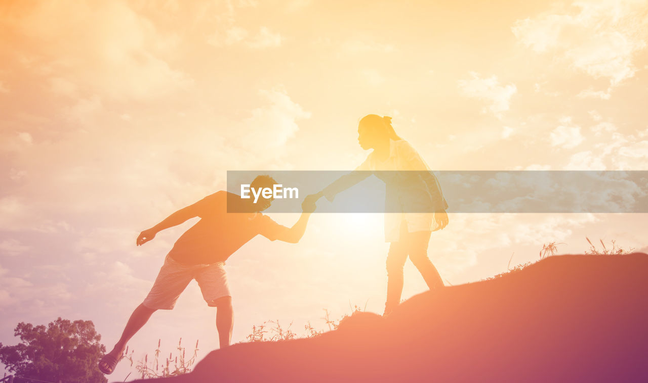 LOW ANGLE VIEW OF MAN AND WOMAN STANDING AGAINST SKY