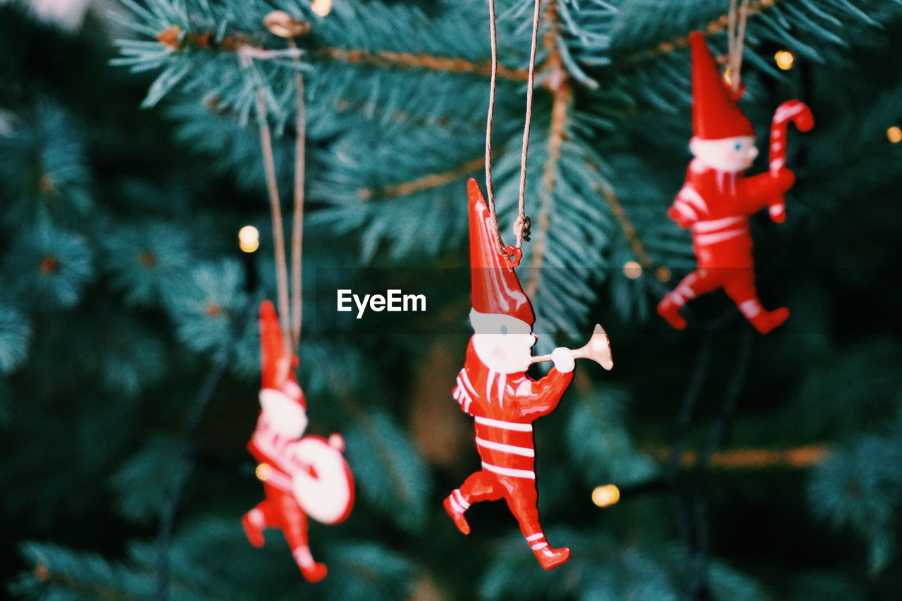 Close-up of red figurines hanging on christmas tree