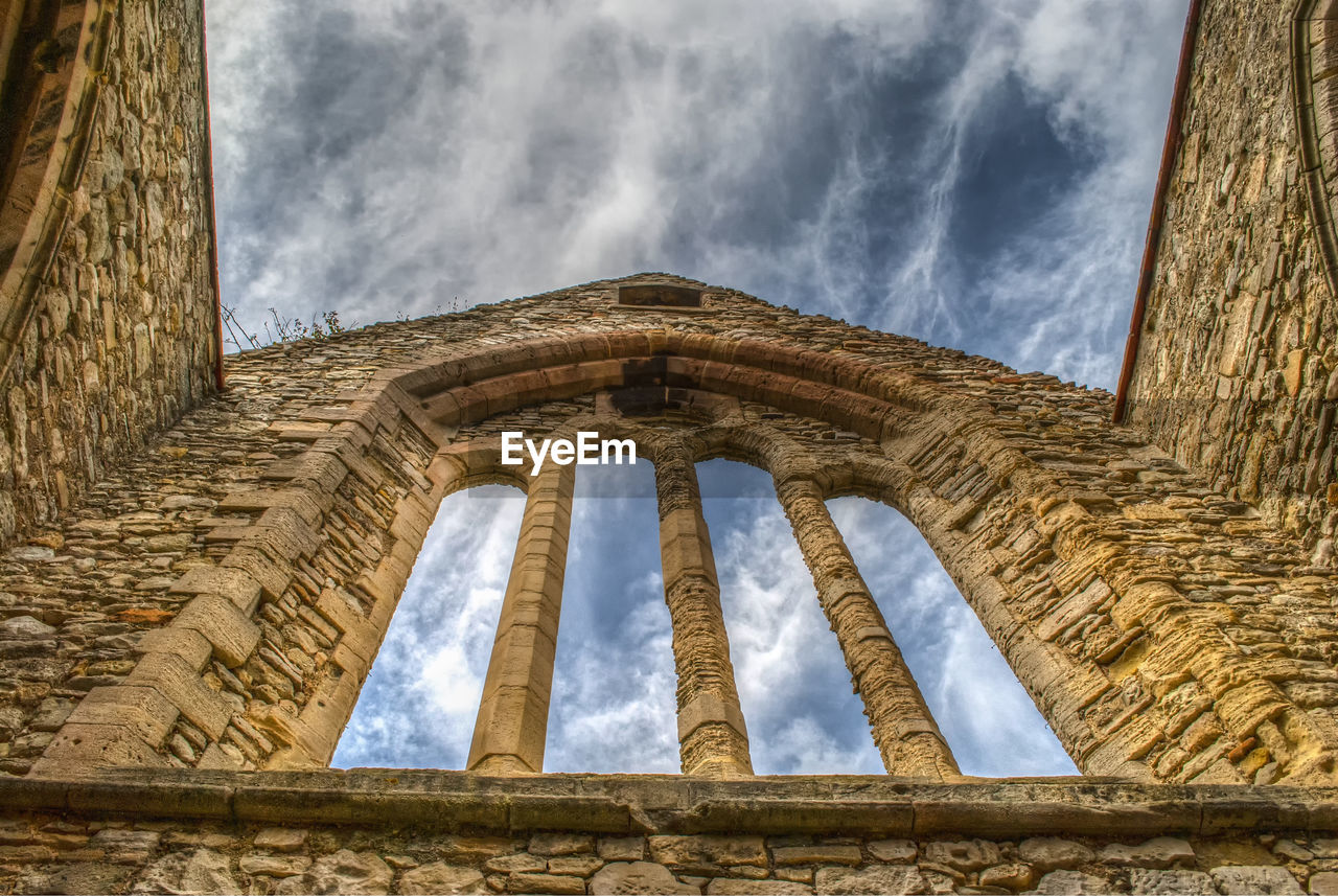 Low angle view of old building against cloudy sky