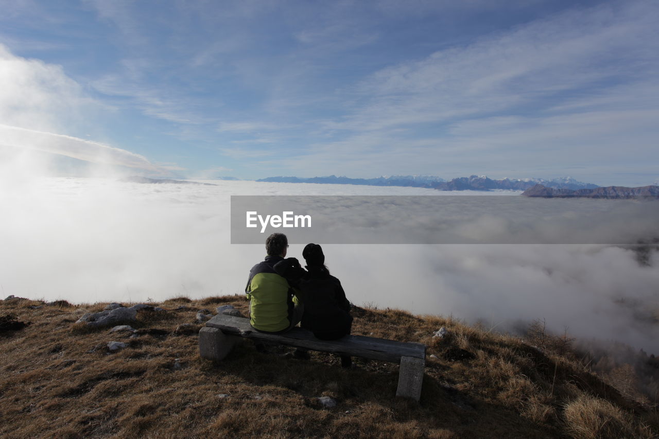 REAR VIEW OF MAN AND WOMAN LOOKING AT VIEW OF LAND