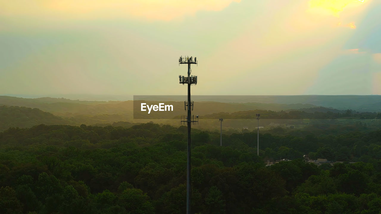 sky, beauty in nature, hill, scenics - nature, morning, environment, nature, landscape, tranquility, tranquil scene, cloud, dawn, no people, sunrise, horizon, sunlight, technology, idyllic, non-urban scene, plant, outdoors, land, electricity, fog, tree, sun, cable, architecture, lighting equipment, wind, religion, rural scene, mist, remote, electricity pylon, green