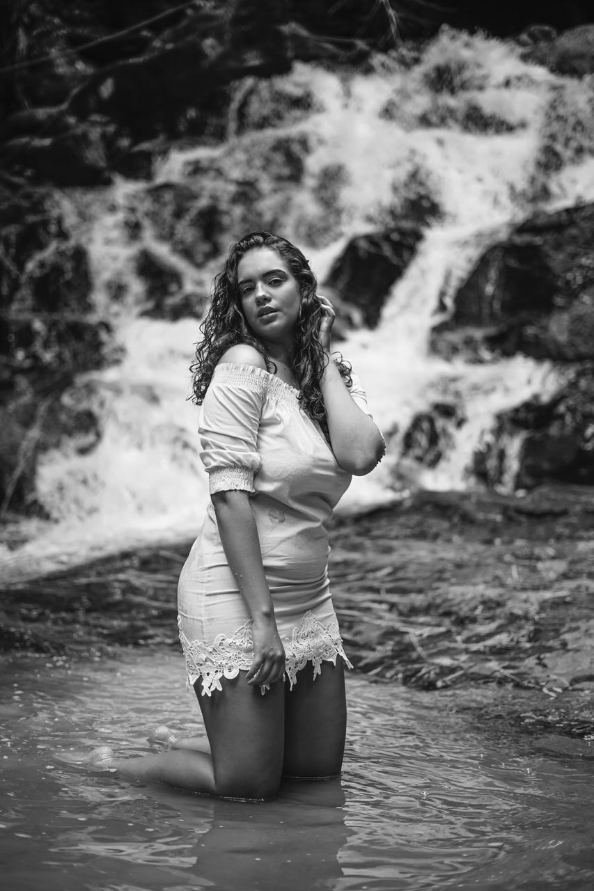 FULL LENGTH PORTRAIT OF WOMAN STANDING IN WATER AT BEACH