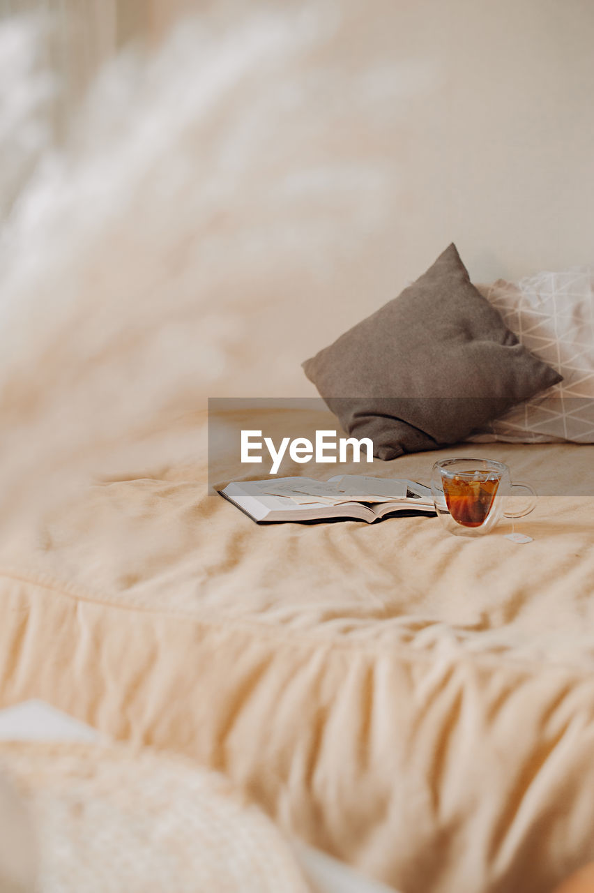 Cozy home. beige bed with pillows, books and cup of tea